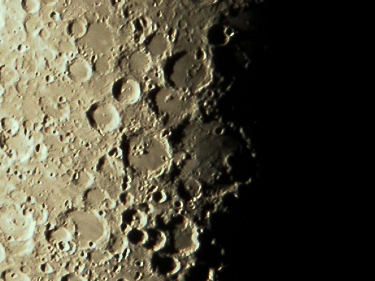 Zu sehen ist ein Ausschnitt der Mondoberfläche, der mit Kratern übersäht ist.