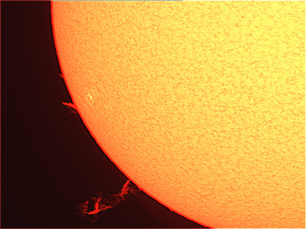 Zu sehen ist das untere linke Viertel der Sonnenoberfläche. Eine Protuberanz, also eine Art Vulkanausbruch auf der Sonnenoberfläche, ist links unten als eine Art rote Flamme zu sehen.